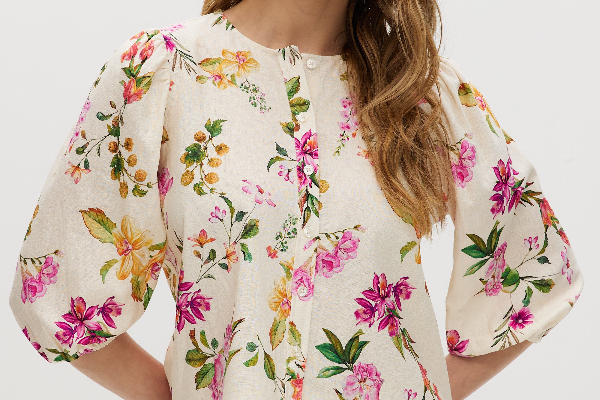Cream floral linen blouse with puff sleeves and button-front closure.