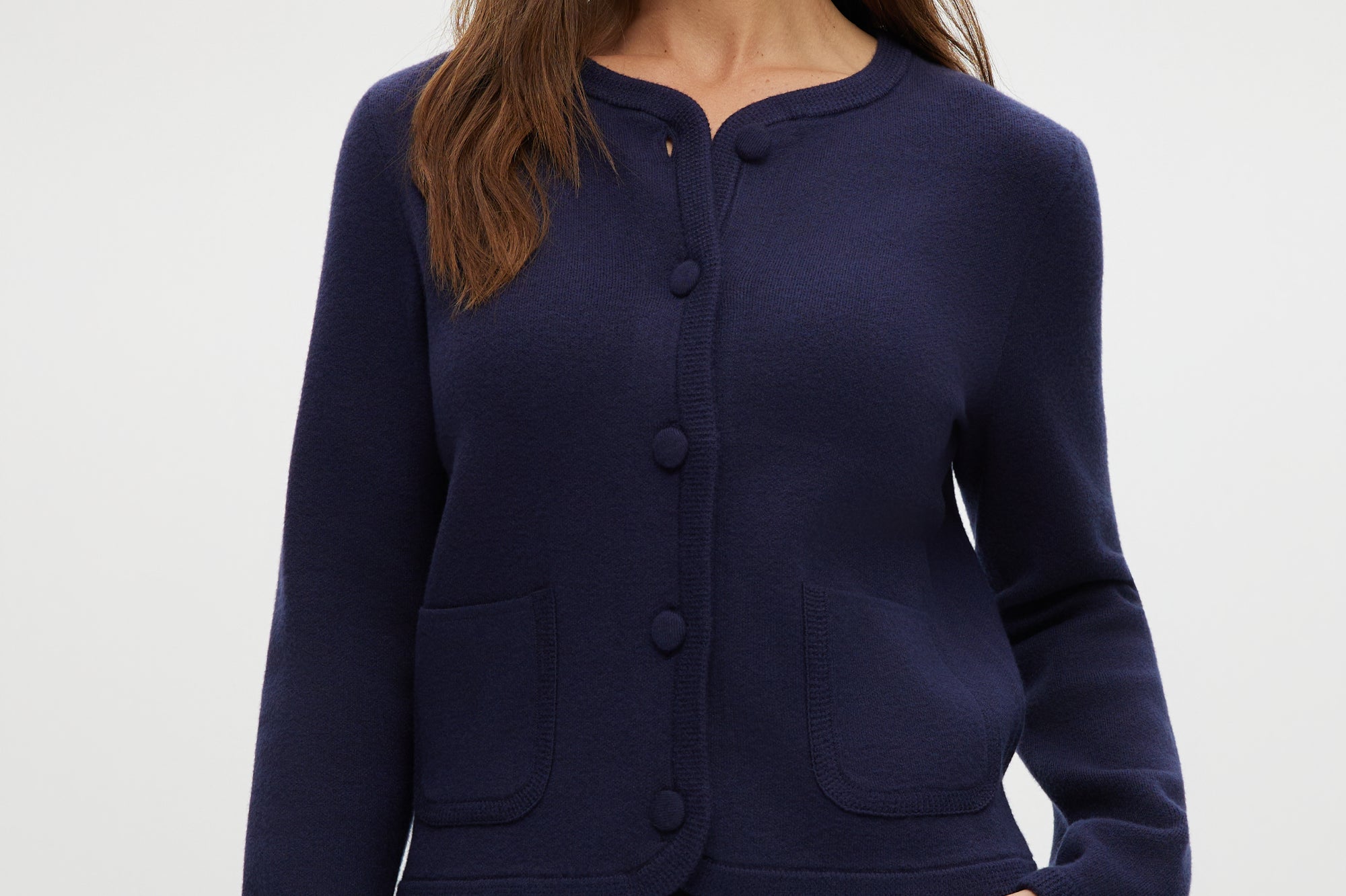 Navy knit cardigan with round collar, long sleeves, and front pockets.