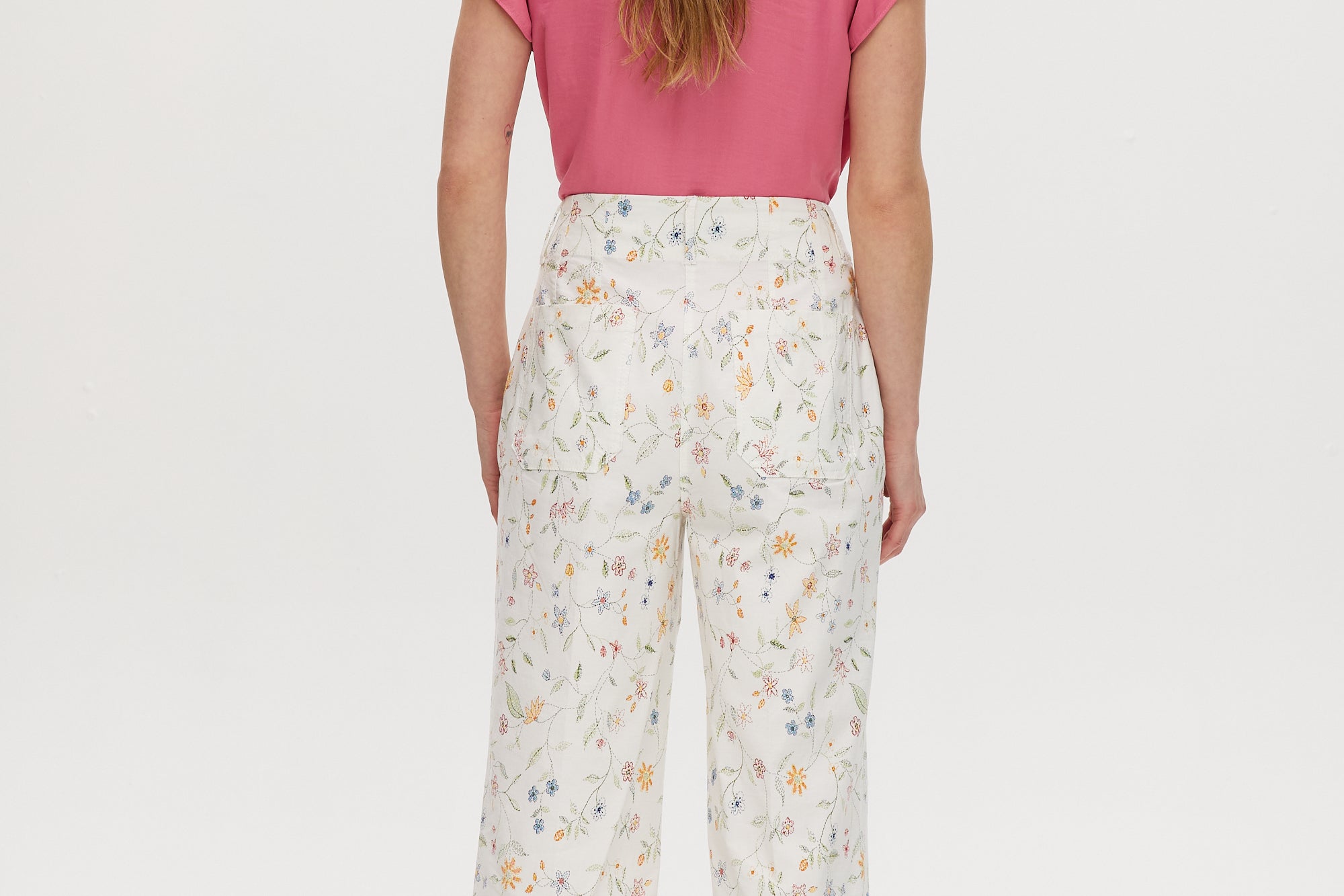 White high-rise straight leg pants with a floral print, button-front closure, and pockets by Hilary Radley.