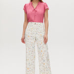 White high-rise straight leg pants with floral print, featuring a button-front closure and pockets.