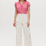 White high-rise straight leg pants with floral print, featuring a button-front closure and pockets.