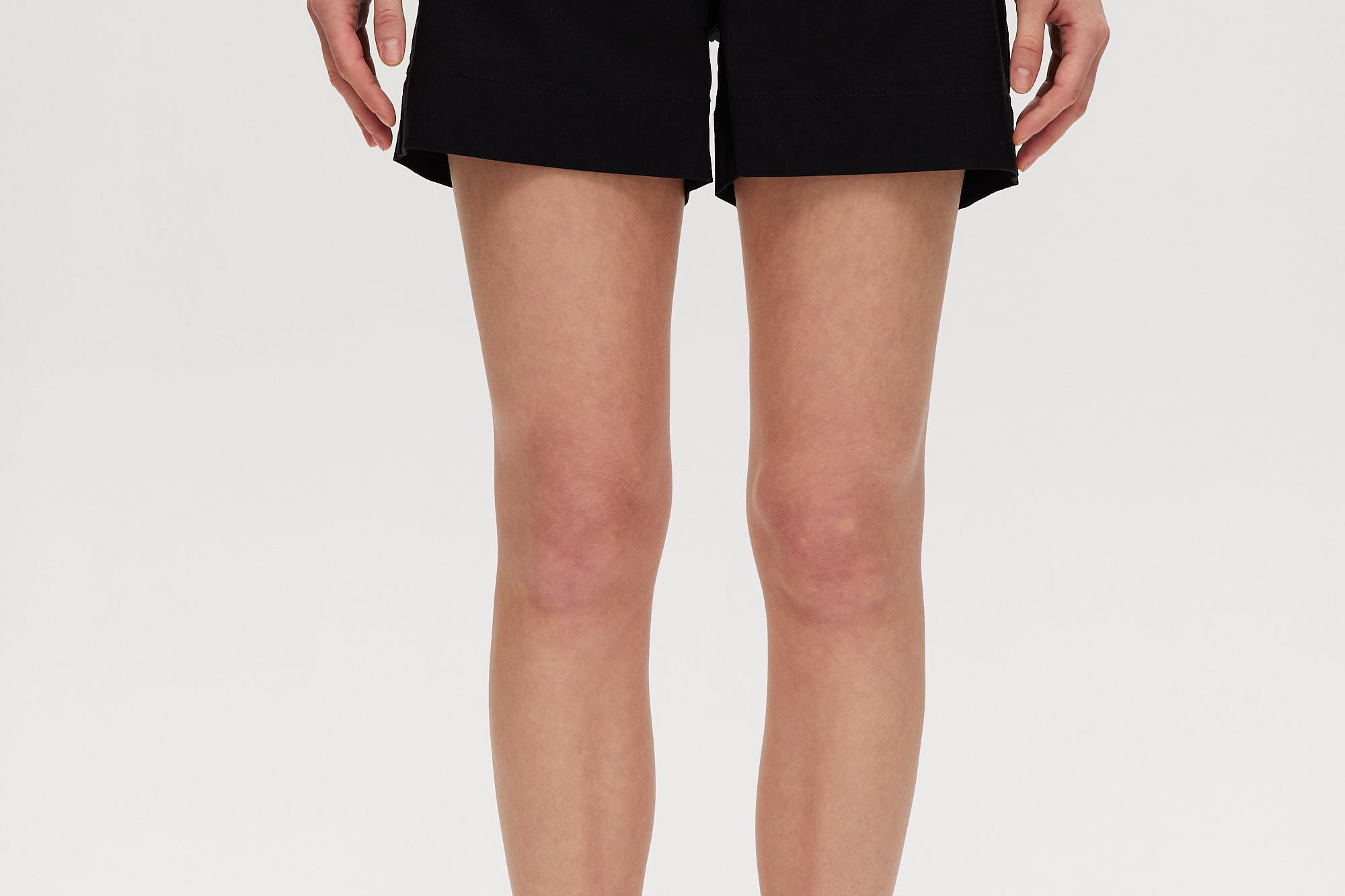 Black high-rise stretch shorts featuring button closure and front patch pockets by Hilary Radley.