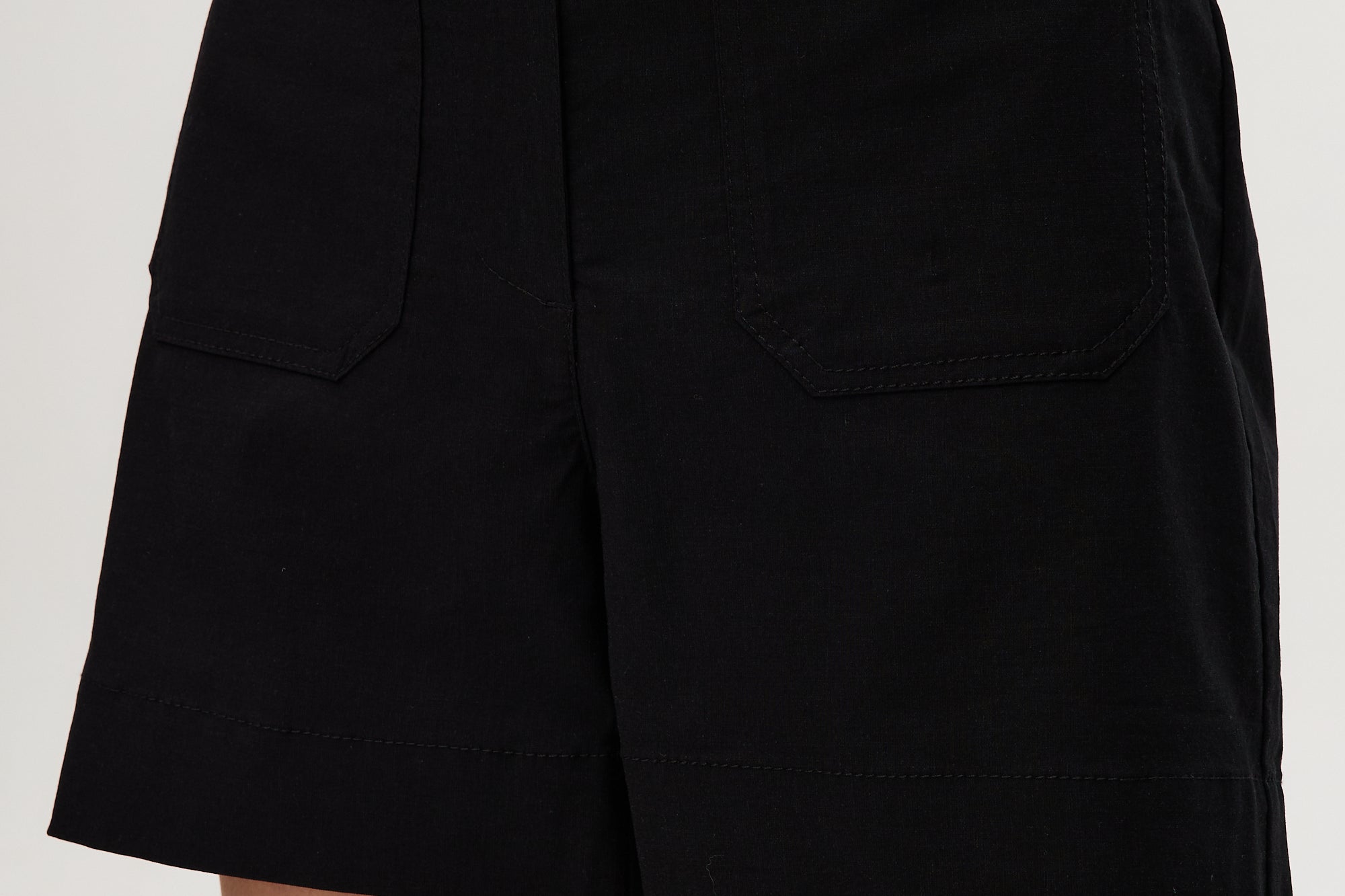 Black high-rise stretch shorts featuring button closure and front patch pockets by Hilary Radley.