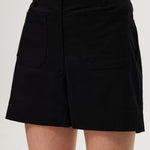Black high-rise stretch shorts featuring button closure and front patch pockets by Hilary Radley.