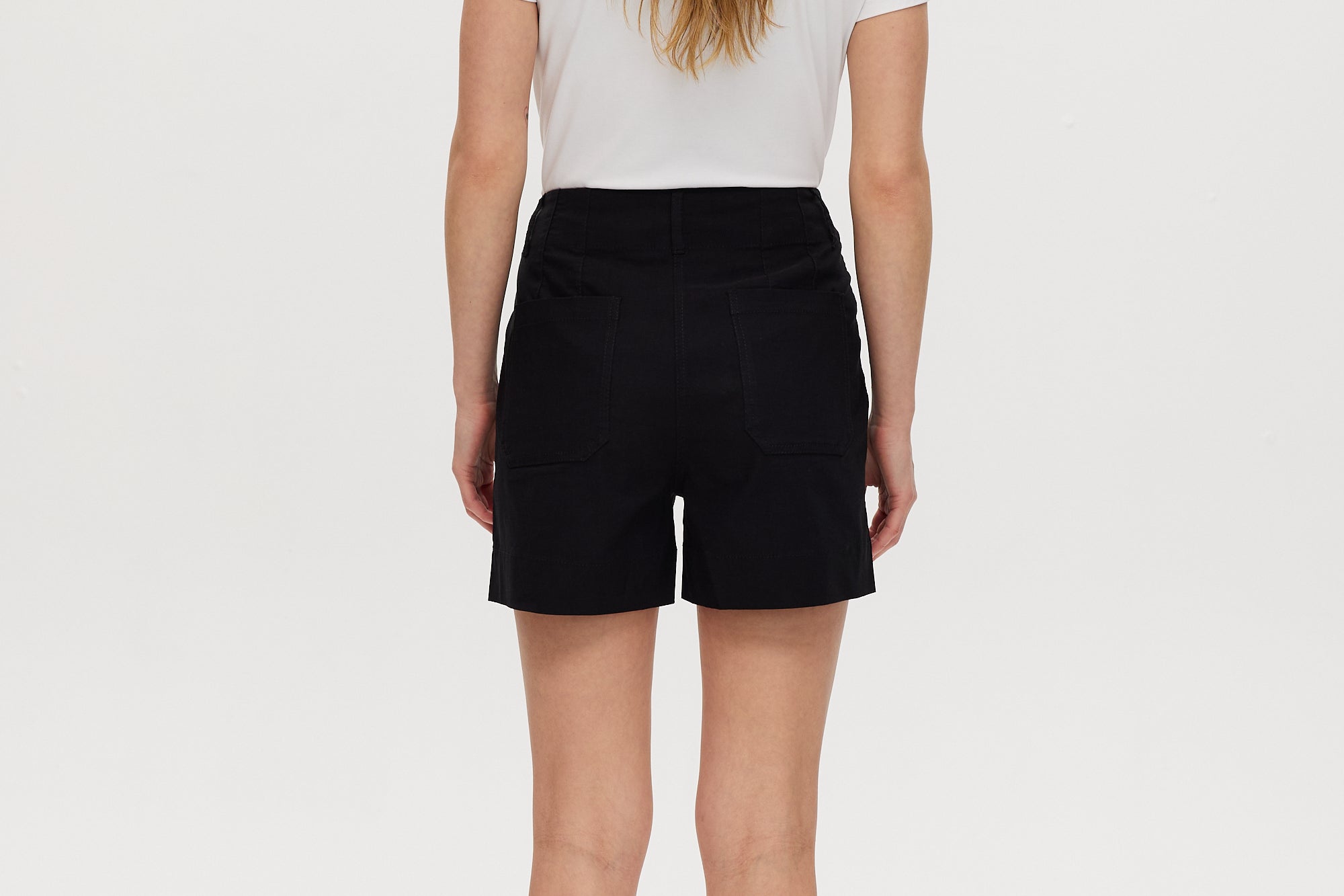 Black high-rise stretch shorts featuring button closure and front patch pockets by Hilary Radley.