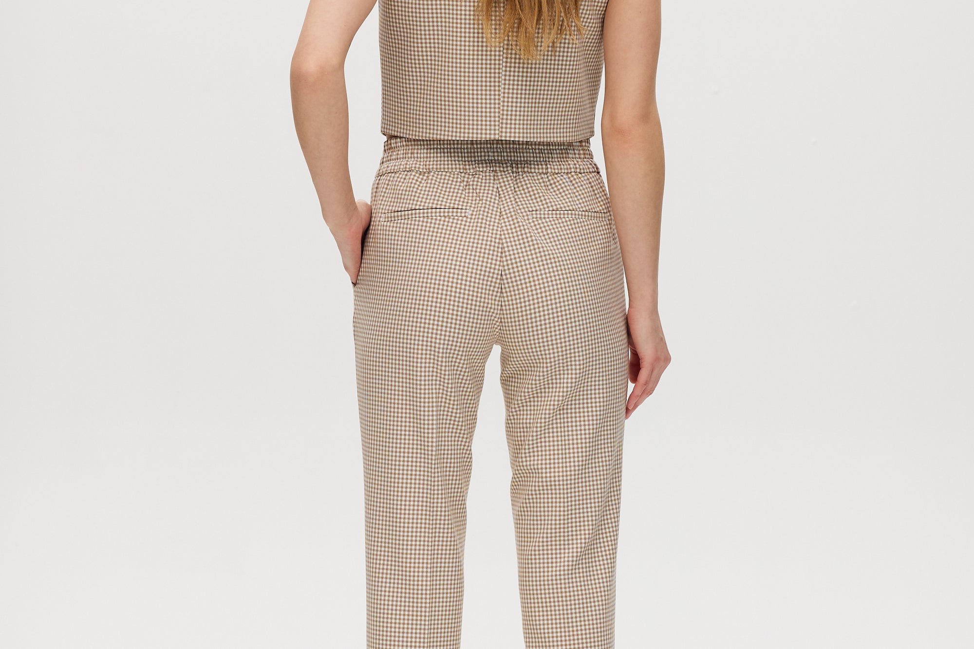 Beige checked slim leg pants featuring a button-front and pockets, part of a vest set by Hilary Radley.