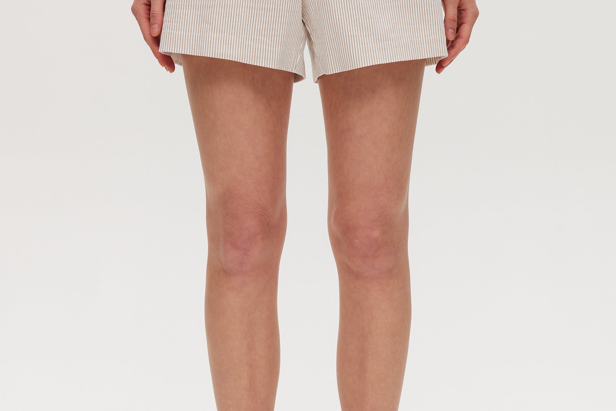 Beige striped pull-on shorts featuring decorative buttons and an elastic waistband by Hilary Radley.