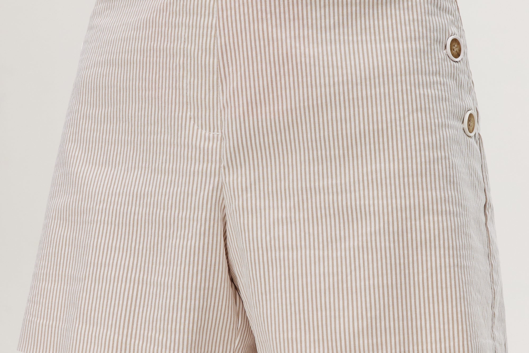 Beige striped pull-on shorts featuring decorative buttons and an elastic waistband by Hilary Radley.