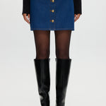 Blue denim mini skirt featuring contrast vegan leather trim and gold buttons by Hilary Radley.