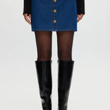 Blue denim mini skirt featuring contrast vegan leather trim and gold buttons by Hilary Radley.