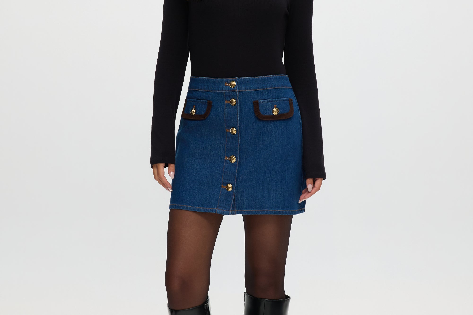 Blue denim mini skirt with contrast vegan leather trim and gold buttons.