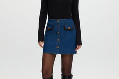 Blue denim mini skirt with contrast vegan leather trim and gold buttons.