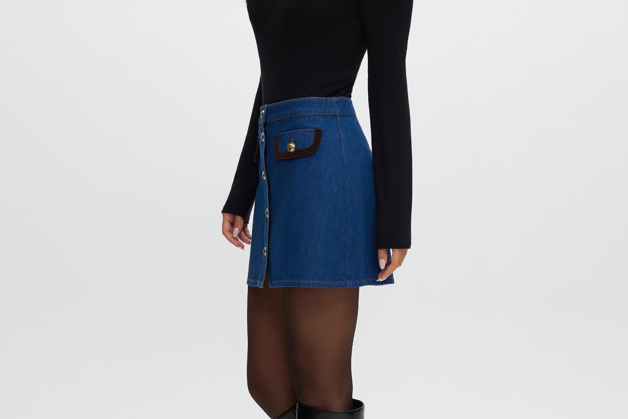 Blue denim mini skirt featuring contrast vegan leather trim and gold buttons by Hilary Radley.