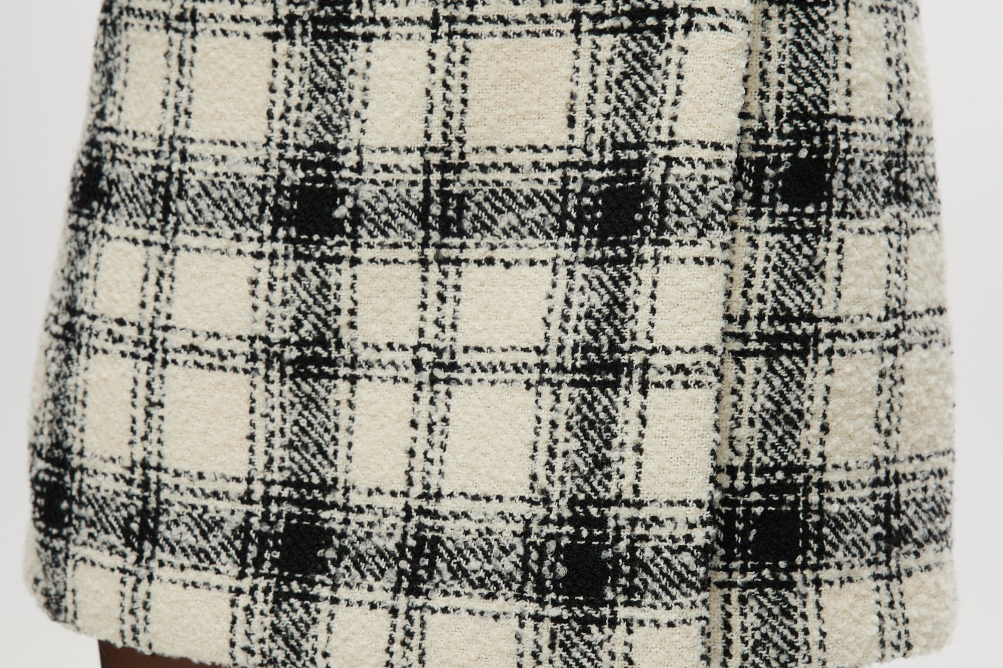 Cream plaid A-line mini skirt featuring a decorative pearl button and boucle texture by Hilary Radley.