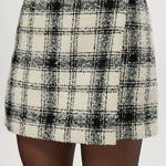 Cream plaid A-line mini skirt featuring a decorative pearl button and boucle texture by Hilary Radley.