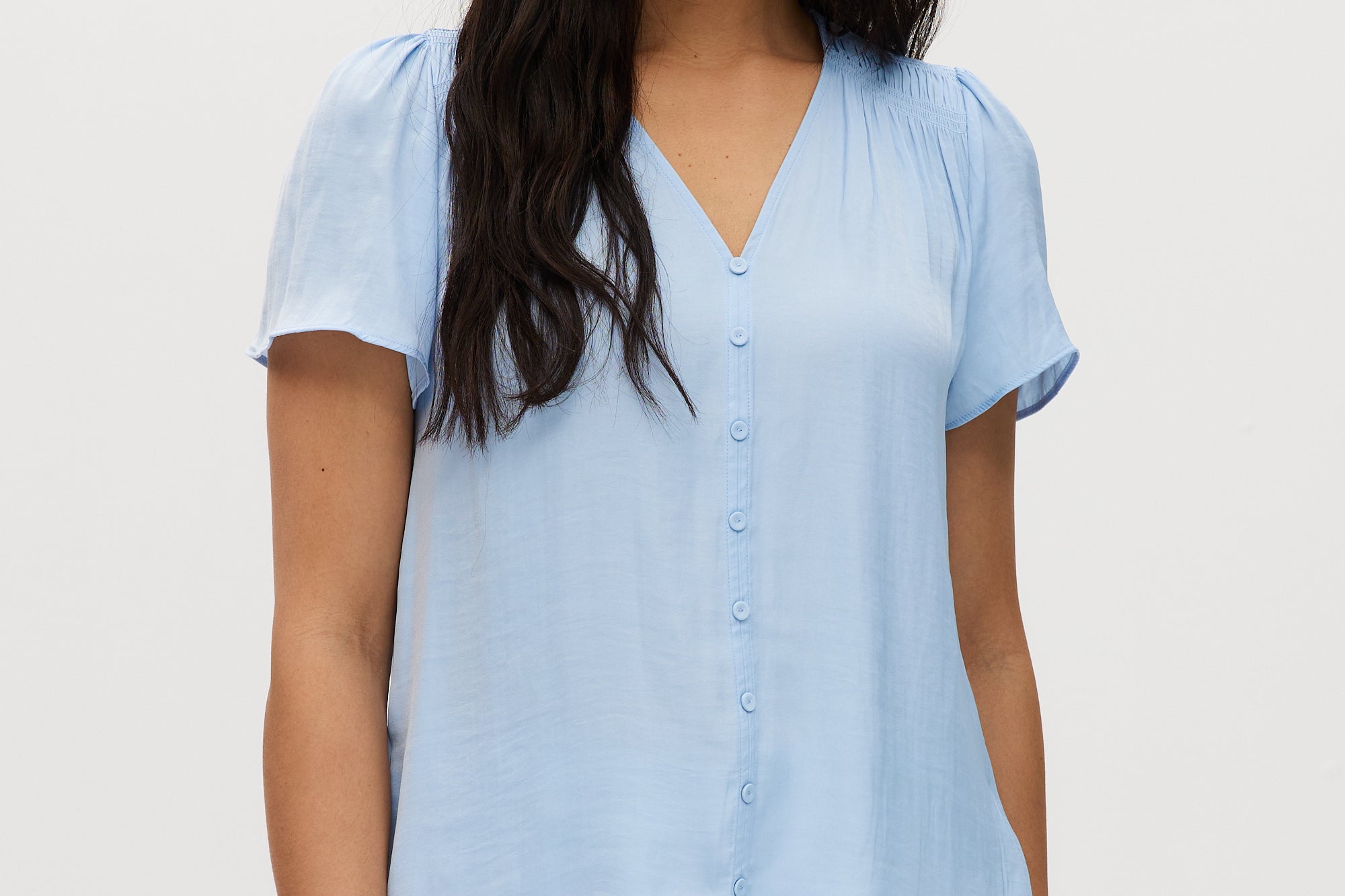 Woman wearing a light blue blouse against a white background