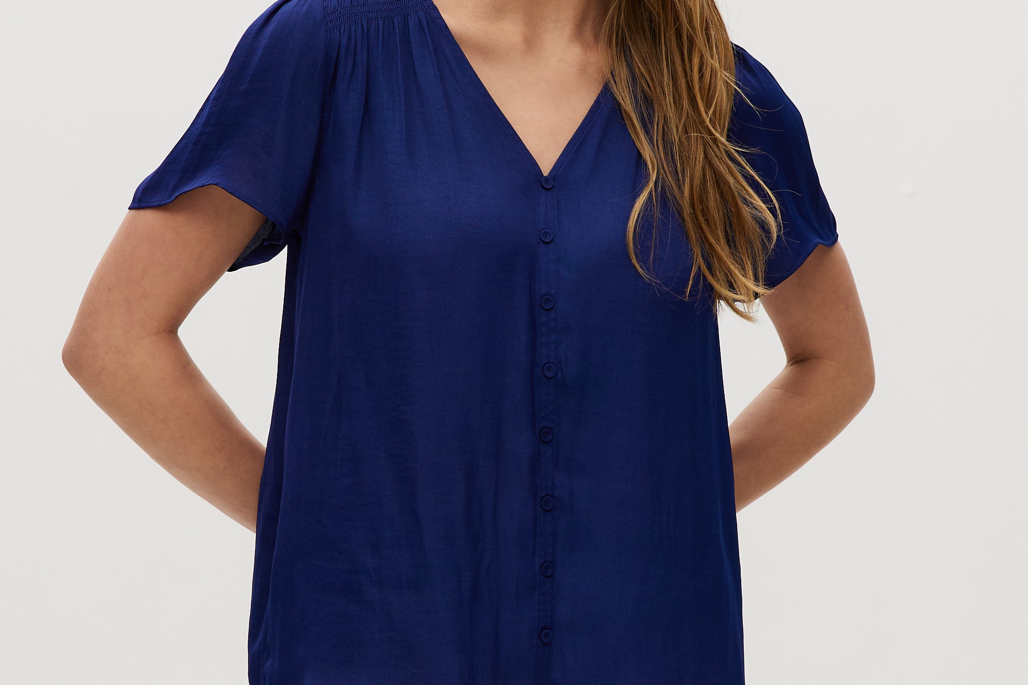 Woman wearing a blue top and checkered shorts on a white background