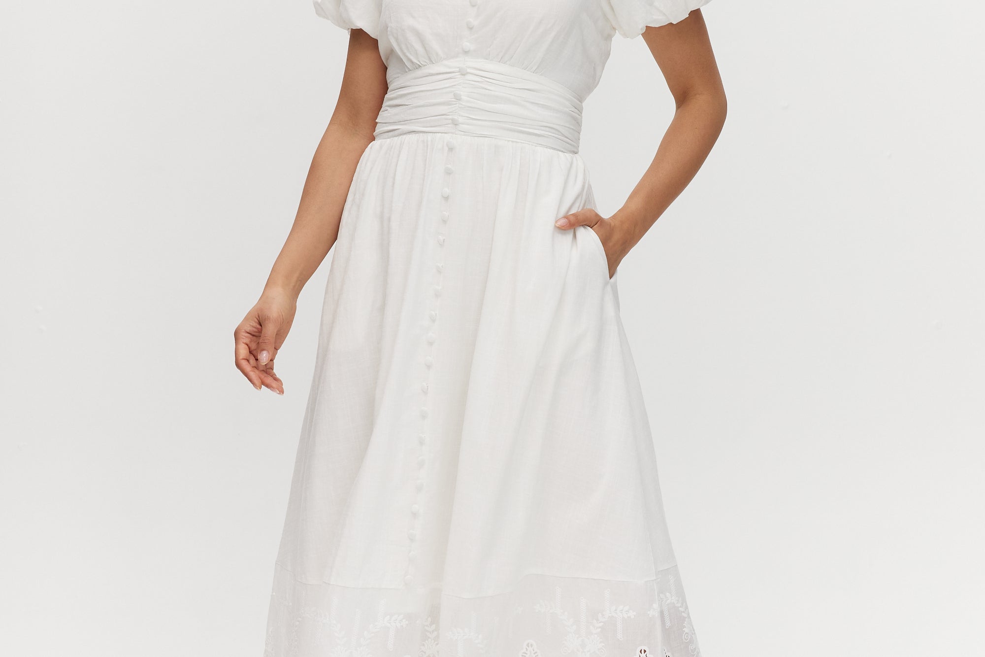 White maxi dress with lace hem, V-neckline, and short balloon sleeves.