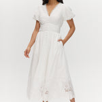 White maxi dress with lace hem, V-neckline, and short balloon sleeves.