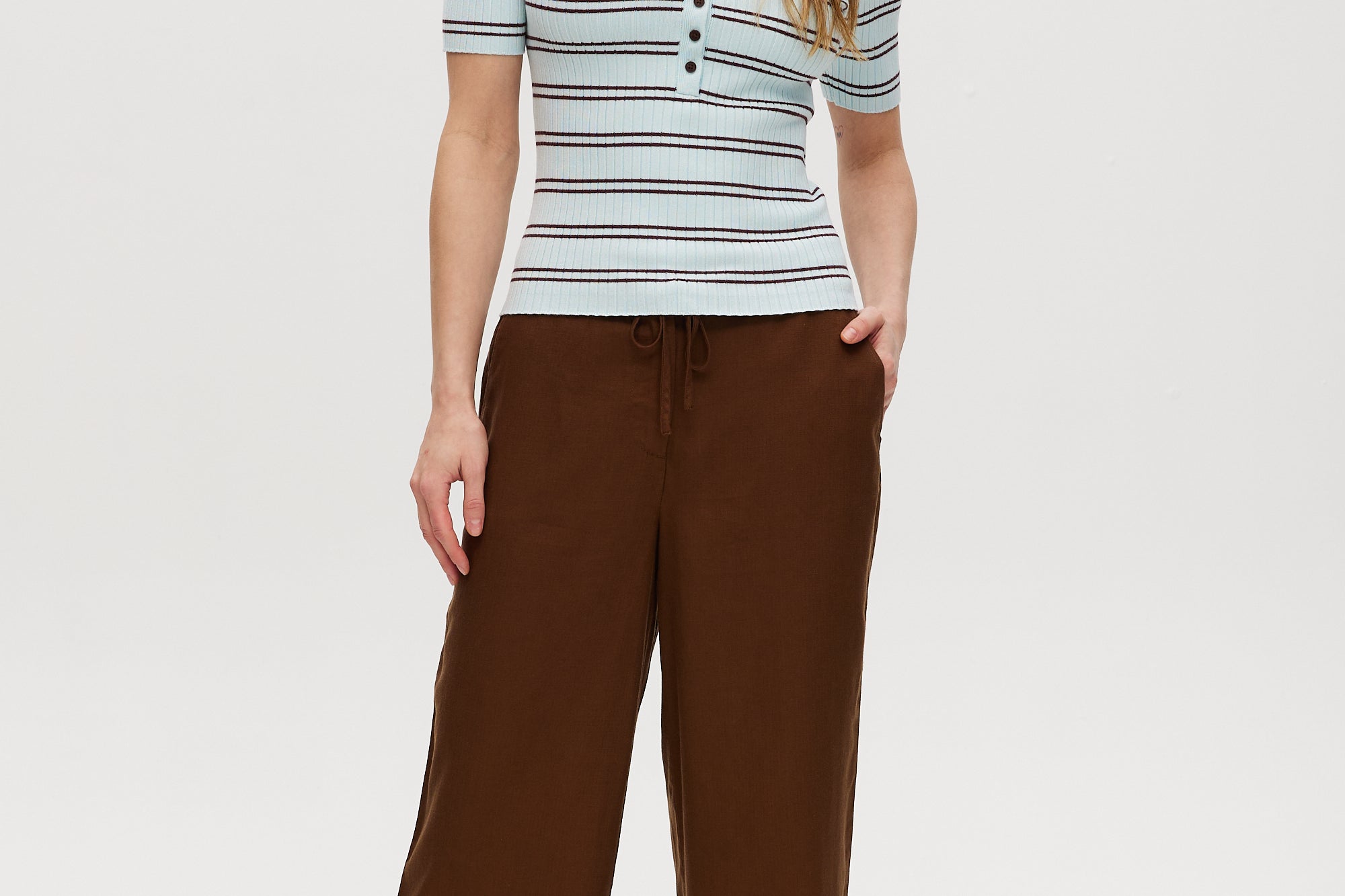Woman wearing a striped shirt and brown pants on a white background