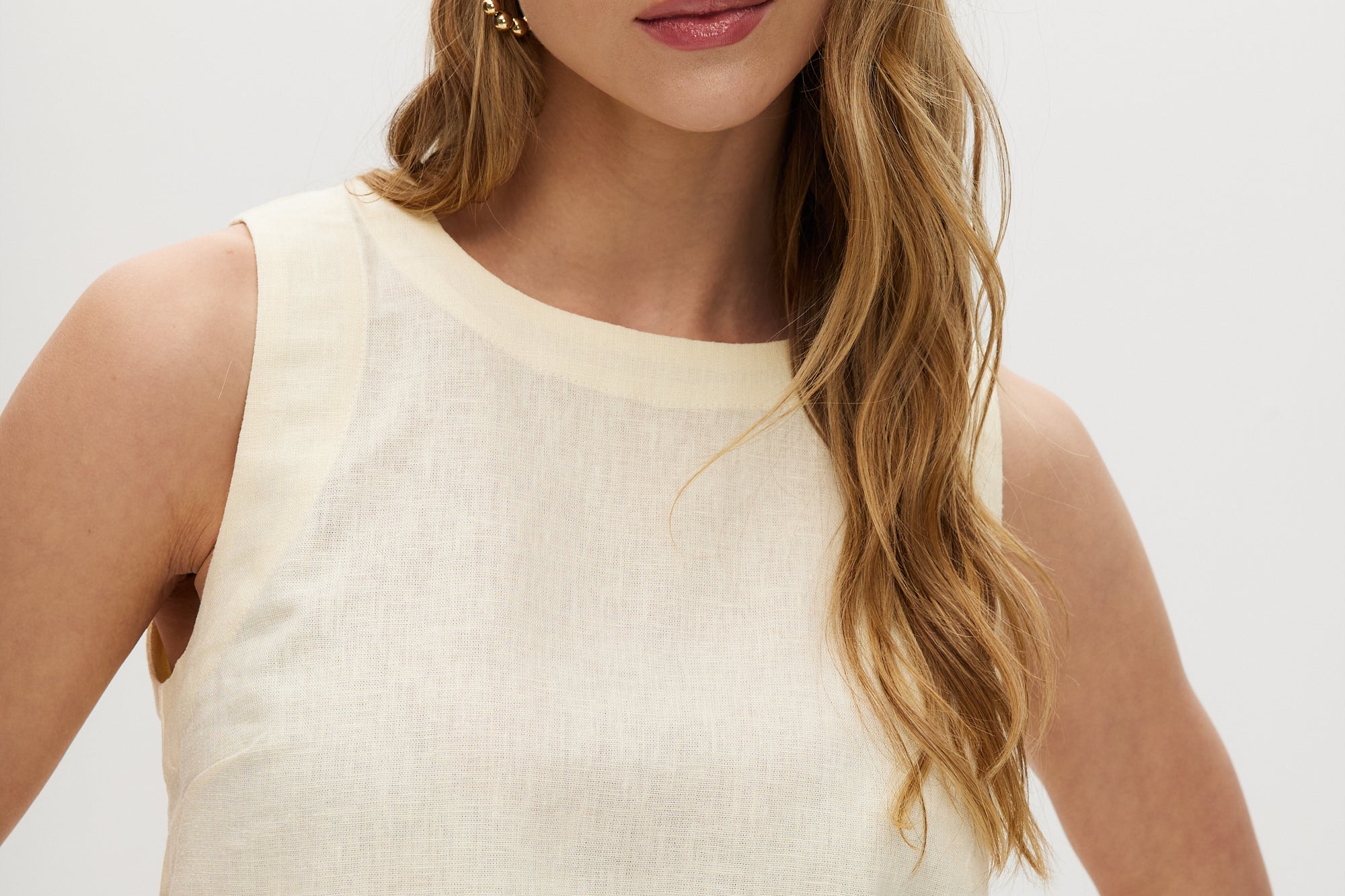 Yellow sleeveless cropped top featuring a crew neckline and tie-back detail by Hilary Radley.