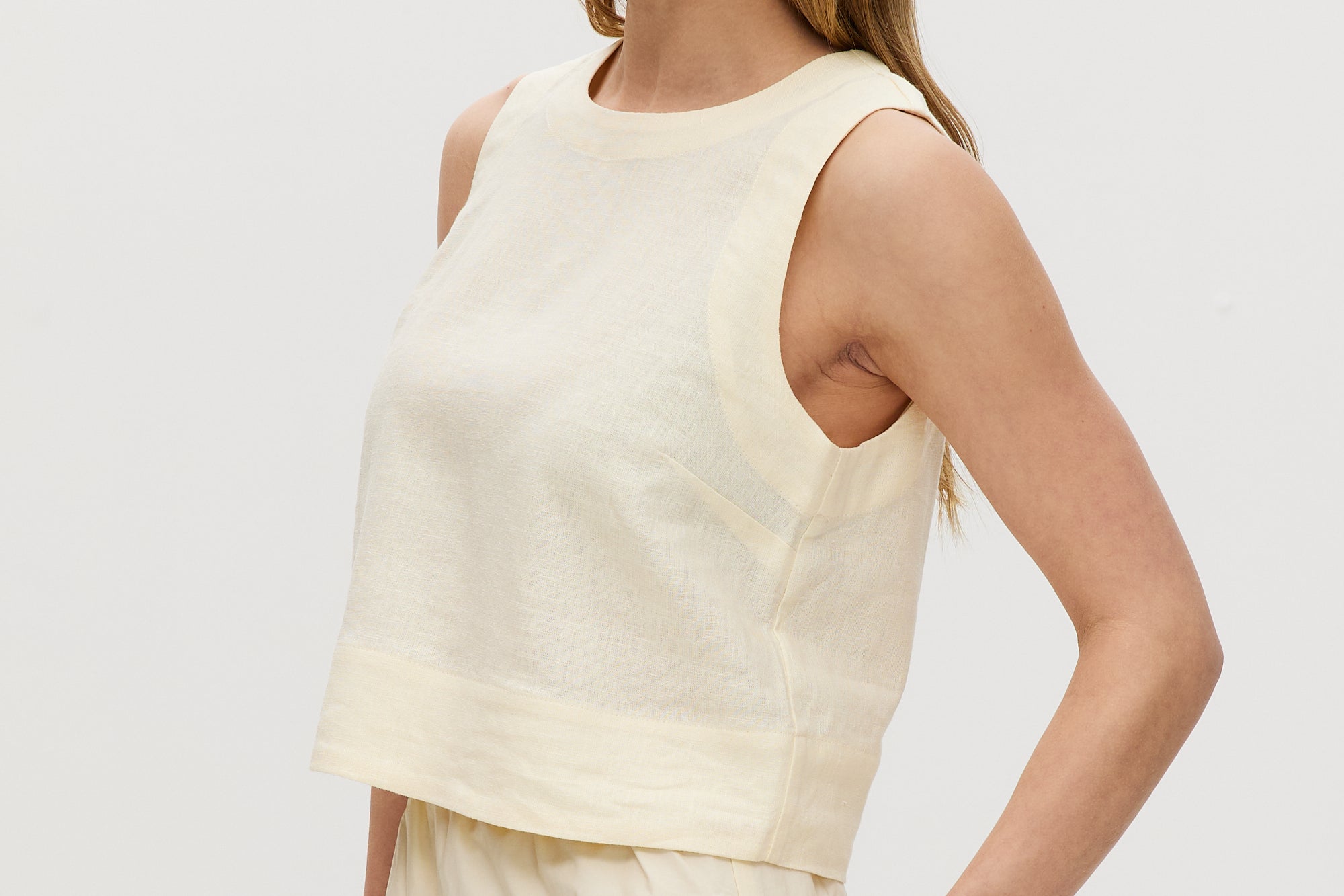 Yellow sleeveless cropped top featuring a crew neckline and tie-back detail by Hilary Radley.