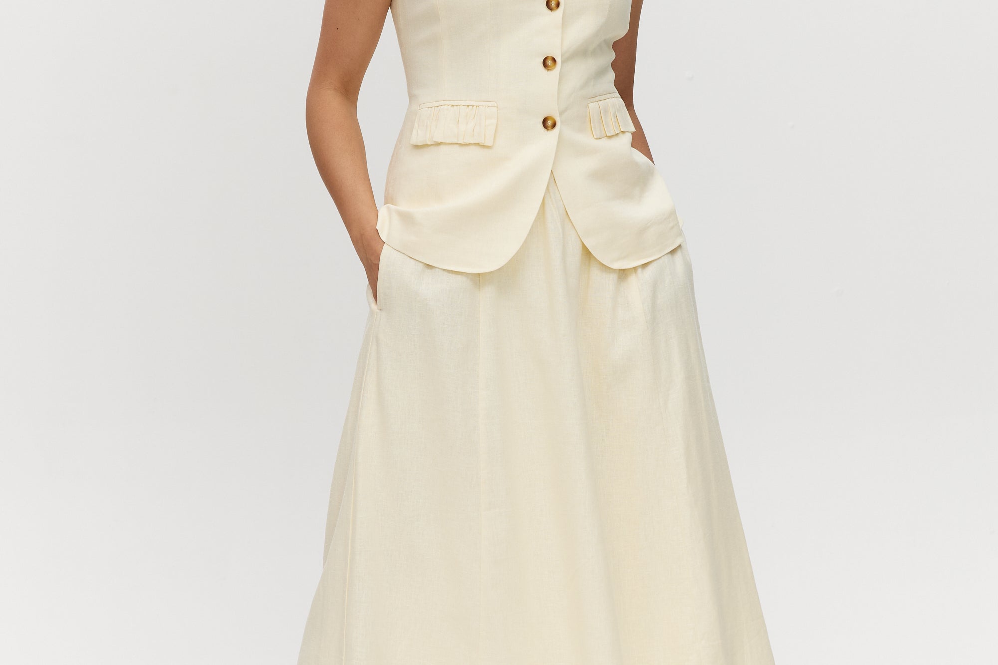 Light cream sleeveless top with button-front and waist tab detail by Hilary Radley.