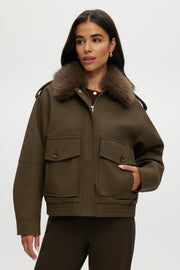 Olive coated jacket with removable faux fur collar, flap pockets, and ribbed hems.