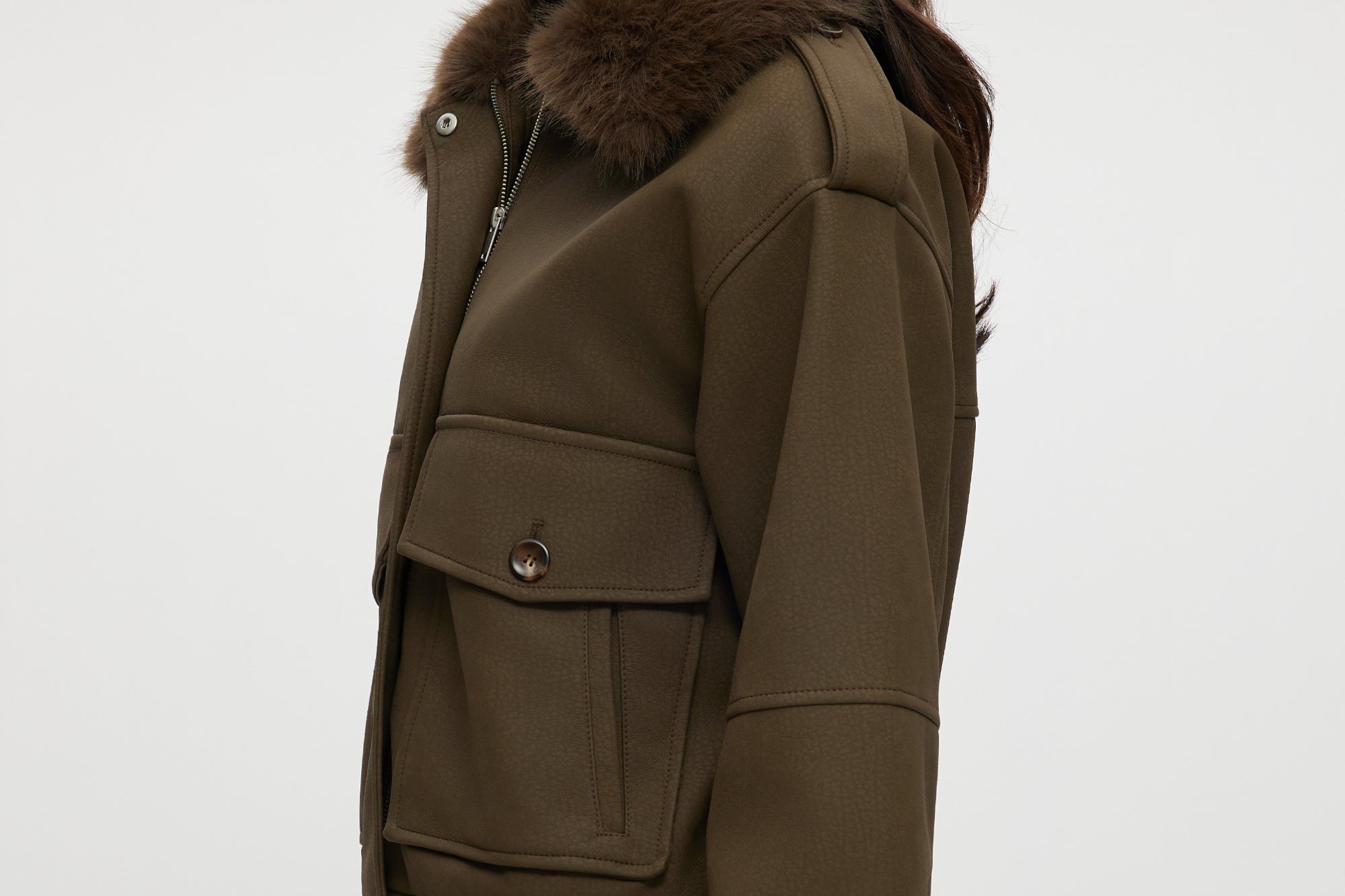 Olive coated jacket featuring a removable faux fur collar, flap pockets, and ribbed hems by Hilary Radley.