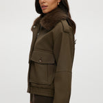 Olive coated jacket featuring a removable faux fur collar, flap pockets, and ribbed hems by Hilary Radley.