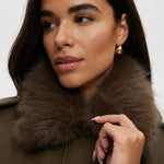 Olive coated jacket featuring a removable faux fur collar, flap pockets, and ribbed hems by Hilary Radley.