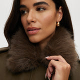 Olive coated jacket featuring a removable faux fur collar, flap pockets, and ribbed hems by Hilary Radley.